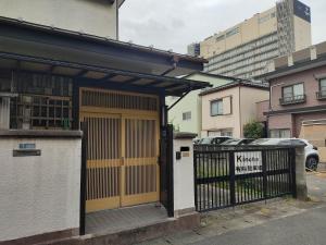 un edificio con una puerta amarilla y una valla en Guesthouse Kincha 駅東口 en Utsunomiya