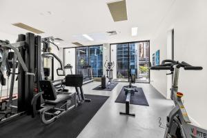 Un gimnasio con cintas de correr y equipos cardiovasculares en un edificio. en 1-Bed Brisbane City Centre with Pool, BBQ & Gym, en Brisbane