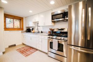 uma cozinha com armários brancos e um frigorífico de aço inoxidável em Luxe Stay W/Hot tub! em Boyne City