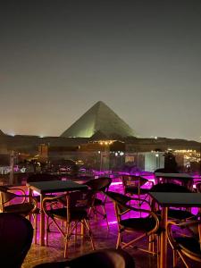 a group of tables and chairs with a pyramid in the background at MAGIC Pyramids Hotel in Cairo