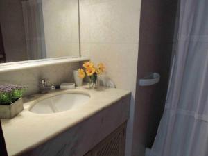 a bathroom sink with a vase of flowers on it at Resolana in Punta del Este