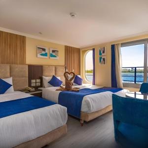 a hotel room with two beds and a window at NILE CRUISE LUXOR & ASWAN نايل كروز الاقصر و اسوان in Luxor