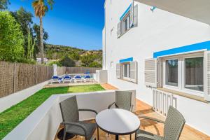 a white house with a patio with chairs and a table at Apartamentos Falcó in Port de Pollensa