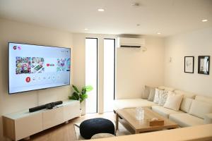 uma sala de estar com um sofá e uma televisão de ecrã plano em Casa Stella 2 Capricorn by Liaison em Osaka
