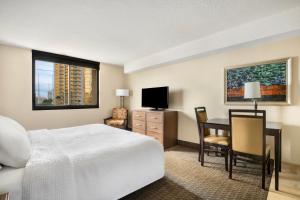 um quarto de hotel com uma cama, uma secretária e uma televisão em The Carriage House em Las Vegas