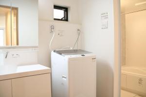 uma cozinha com um frigorífico branco e um lavatório em Casa Stella 2 Capricorn by Liaison em Osaka