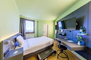 a bedroom with a bed and a desk and a tv at mk hotel remscheid in Remscheid