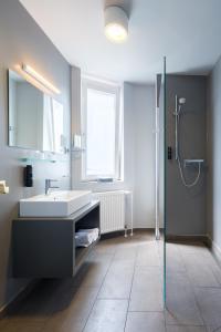 La salle de bains est pourvue d'un lavabo et d'une douche en verre. dans l'établissement mk hotel remscheid, à Remscheid