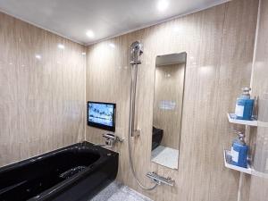 a bathroom with a tub and a tv on the wall at Hotel BaliBali 鶯谷 in Tokyo