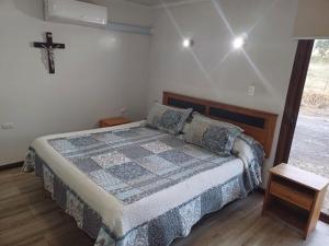 um quarto com uma cama e uma cruz na parede em Parcela Zurich, casa 1 em Angol