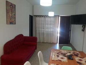 a living room with a red couch and a table at FRIDA APARTMENT remis gratis a Ezeiza in Ezeiza