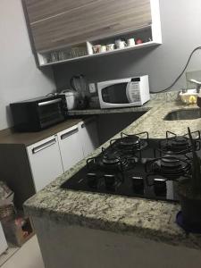 a kitchen with a stove and a microwave at Lugar pra relaxar...Perto de tudo .. in Búzios +3 photos