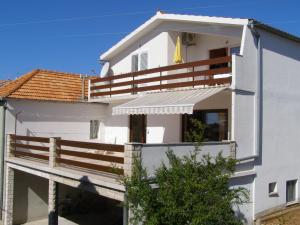 a white house with a wooden balcony at Apartments Prgin in Primošten