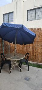 a blue umbrella sitting on a table with two chairs at Alojamiento en Luján de Cuyo in Ciudad Lujan de Cuyo