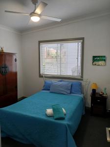 a bedroom with a blue bed and a window at Our Retreat in Forster