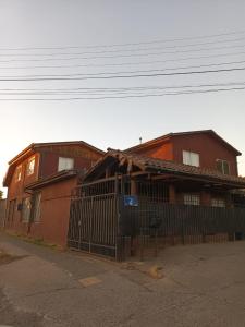 una casa roja con una valla delante en Hospedaje JM, en Chillán