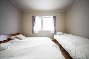 two beds in a room with a window at Learch Asahikawa in Asahikawa +52 photos