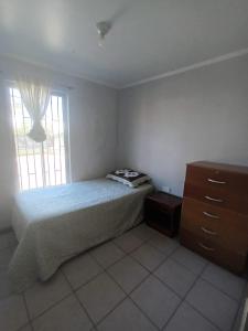 a bedroom with a bed and a dresser and a window at Hospedaje JM in Chillán