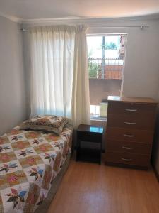 a bedroom with a bed and a dresser and a window at Hospedaje JM in Chillán