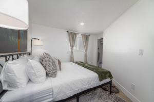 um quarto com uma cama com lençóis brancos e almofadas em Quaint 1 BD 1 BTH Guest Home Minutes from Gonzaga em Spokane