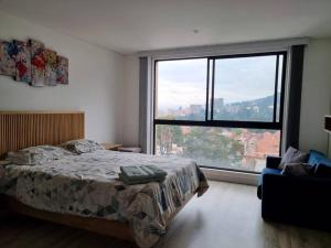 um quarto com uma cama e uma grande janela em Loft en Centro Internacional con Vista Increíble em Bogotá