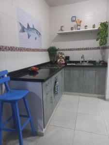 a kitchen with a counter and a blue stool at CABAÑA A POCA DISTANCIA DE BQA in Puerto Colombia