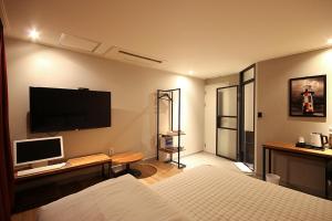een hotelkamer met een bed en een televisie aan de muur bij Hey Day Hotel in Busan