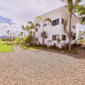 een wit huis met palmbomen en een grindoprit bij Modern home with pool in Hone Creek