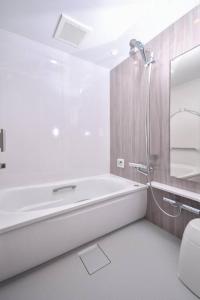 uma casa de banho branca com uma banheira e um chuveiro em GuestHouseYULLAT em Horiechō
