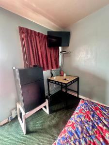a bedroom with a desk and a bed with a television at Your Motel in Ypsilanti