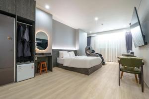 a bedroom with a bed and a desk and a chair at H-Evian Hotel in Gwangju