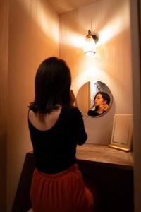 a woman looking at her reflection in a mirror at 旅宿うさぎとかめ Guest House USAGI to KAME 近江八幡中心地 ヴォーリズ建築好きにお勧め in Hachiman
