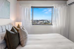 a bedroom with a large window and a bed with pillows at 2-Bed near Beach with BBQ & Stunning Ocean Views in Alexandra Headland