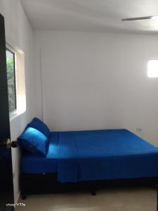 Cama azul en habitación blanca con ventana en Apartamento Erika 301 en el centro de Santa Marta, en Santa Marta