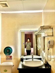 een vrouw die een foto neemt van een badkamerspiegel bij Keypad Hotel - 87 Nguyễn Khang in Hanoi