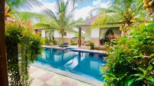 a swimming pool in front of a house with palm trees at Dong Loka Guesthouse Bali in Payangan
