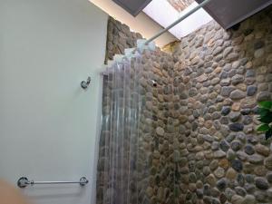 a bathroom with a shower with a stone wall at CASA RAÍZ RÍO ANCHO in Mingueo