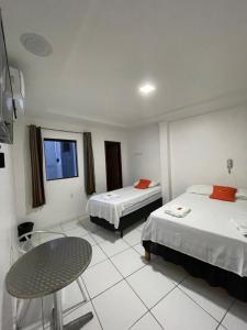 um quarto de hotel com duas camas e uma mesa em Hotel Pousada Acauã Acesso através de escadas em Campina Grande