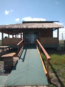 uma passagem de madeira que leva a uma casa com telhado de palha em Wild Wetlands Lodge em Ituzaingó