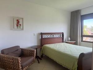 1 dormitorio con 1 cama, 1 silla y 1 ventana en Gardel é Destino Floripa Apartamento 2 quartos, en Florianópolis