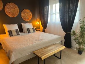 1 dormitorio con 1 cama con banco de madera junto a una ventana en Appartement 2 chambres Sainte-Luce, en Sainte-Luce