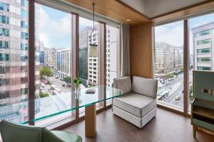 Humble Boutique Hotel في تايبيه: طاولة زجاجية وكرسي في غرفة مع نوافذ كبيرة
