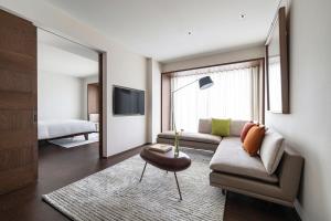 Humble Boutique Hotel في تايبيه: غرفة معيشة مع أريكة وتلفزيون
