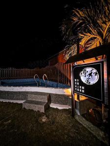 a sign with two birds sitting on a bench at night at 源和居旅宿 in Xiaoliuqiu