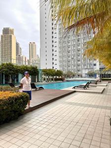 Makati SM Jazz Residence Staycation Condo with balcony في مانيلا: امرأة تقف بجانب مسبح في مدينة