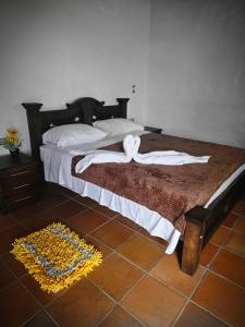 1 dormitorio con 1 cama con sábanas blancas y suelo marrón en Finca Mr Bueno, en Barichara