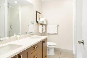 a white bathroom with a sink and a toilet at Penthouse Lake Home - 3BR w/Amazing View & Deck! in Harrison Hot Springs