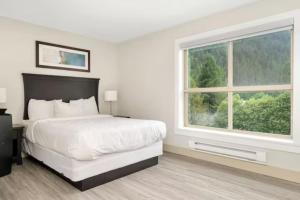 Habitación blanca con cama y ventana en Penthouse Lake Home - 3BR w/Amazing View & Deck!, en Harrison Hot Springs