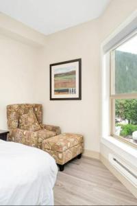 1 dormitorio con silla, cama y ventana en Penthouse Lake Home - 3BR w/Amazing View & Deck!, en Harrison Hot Springs