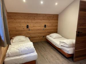 two beds in a room with wooden walls at Chalet Cristal II in Les Contamines-Montjoie